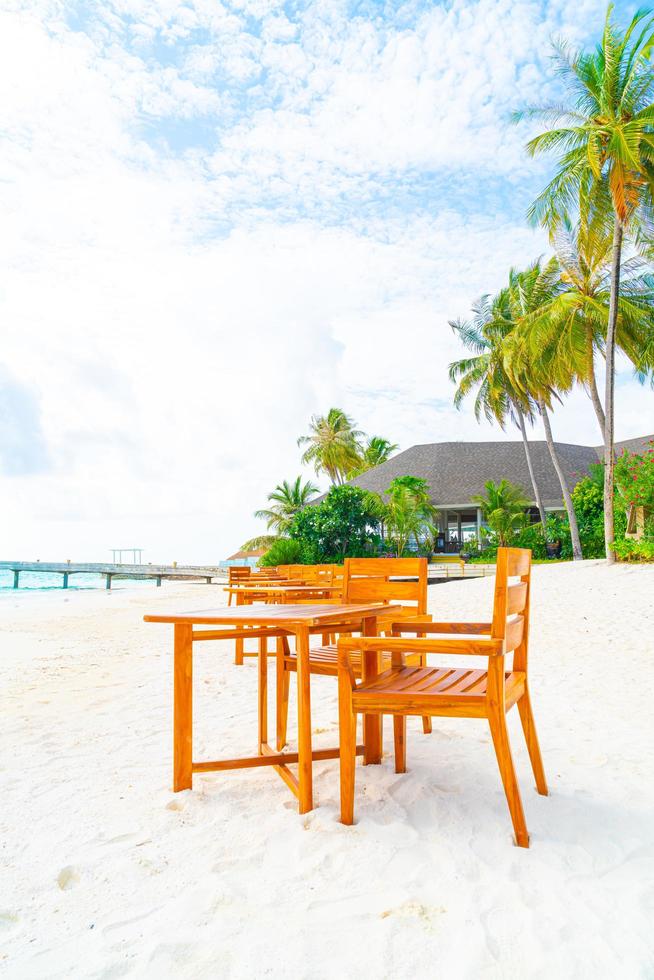 Empty wood table and chair on beach with sea view background in Maldives photo