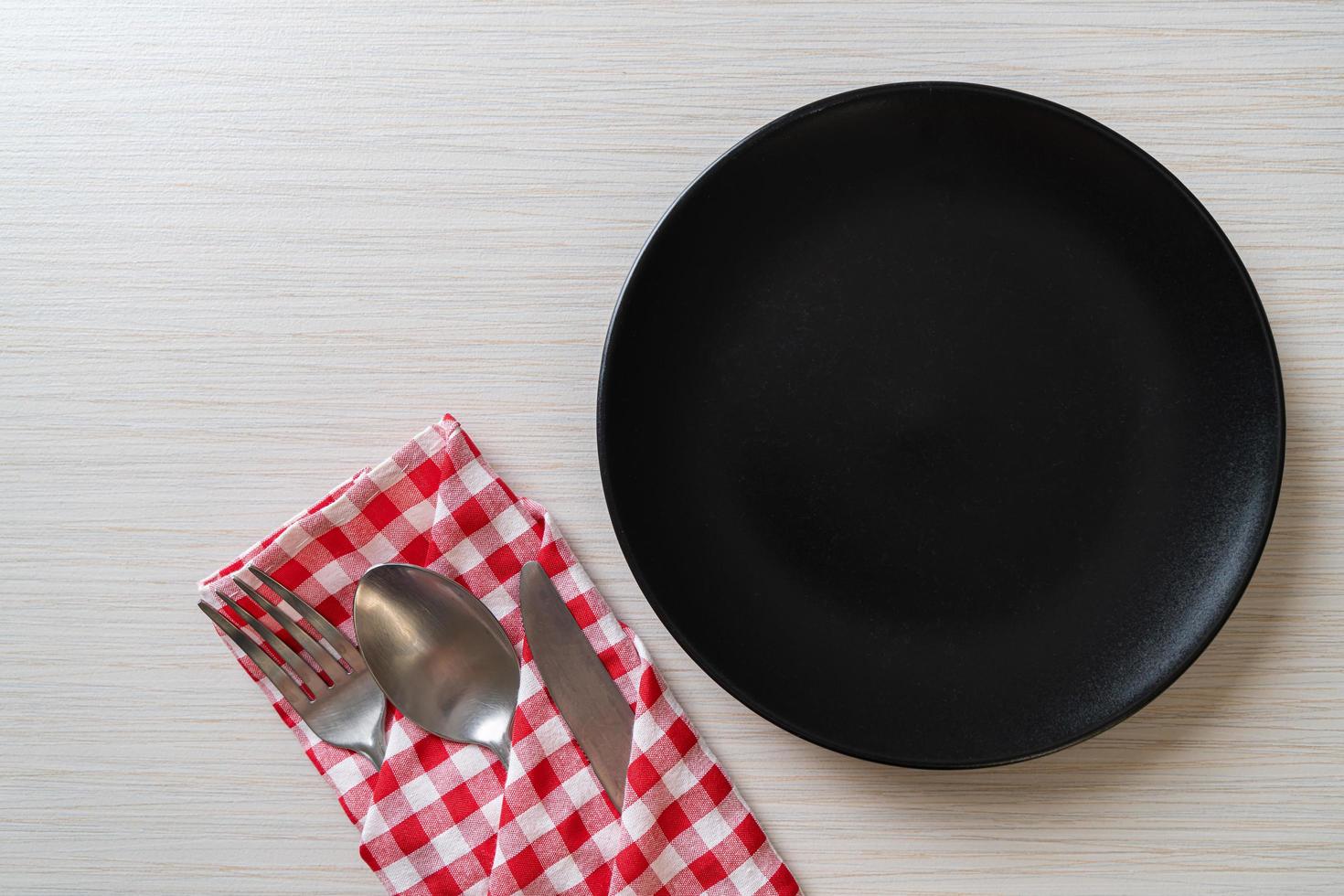 Empty plate or dish with knife, fork, and spoon on wood tile background photo