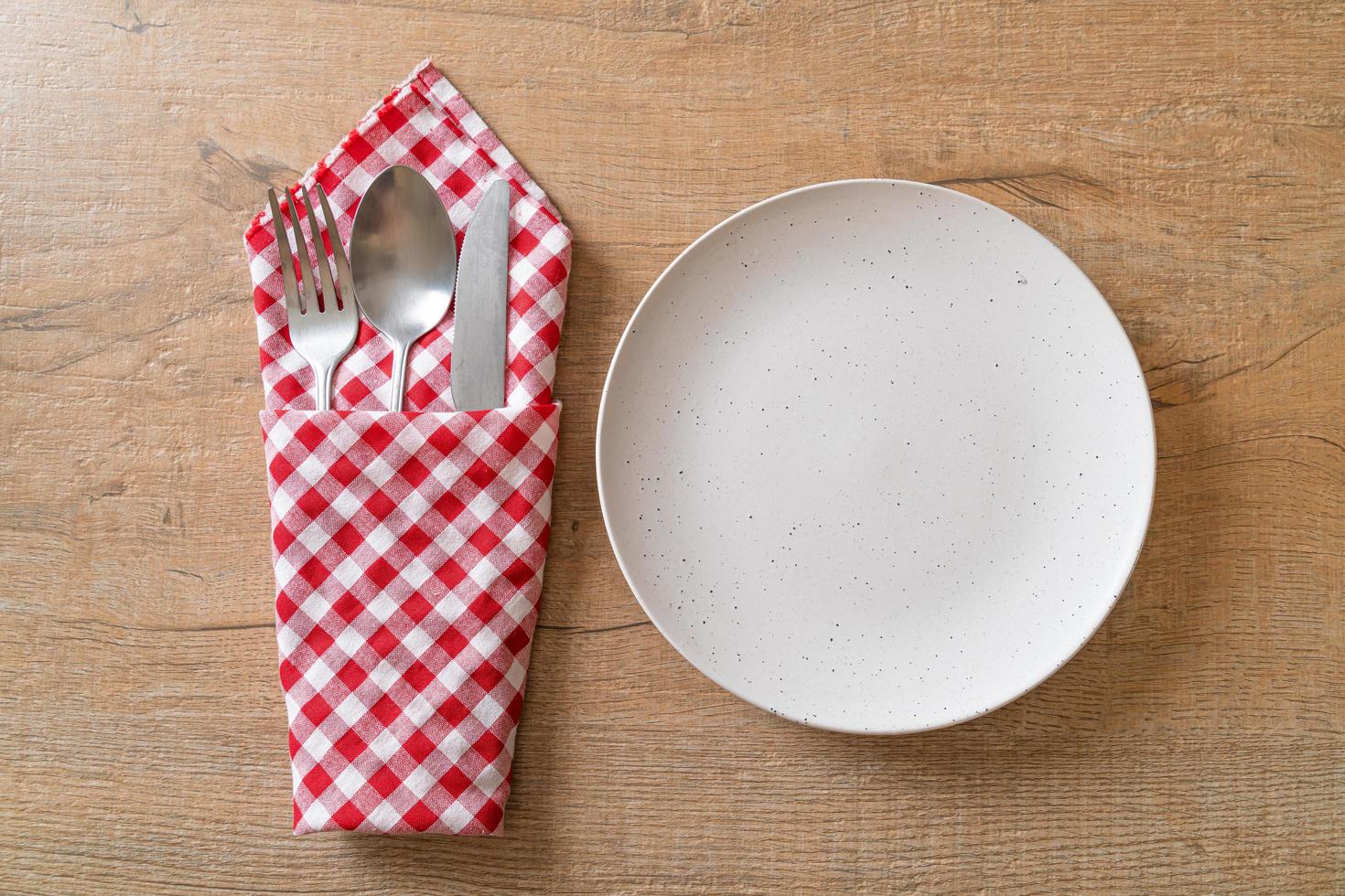 Empty plate or dish with knife, fork, and spoon on wood tile background photo