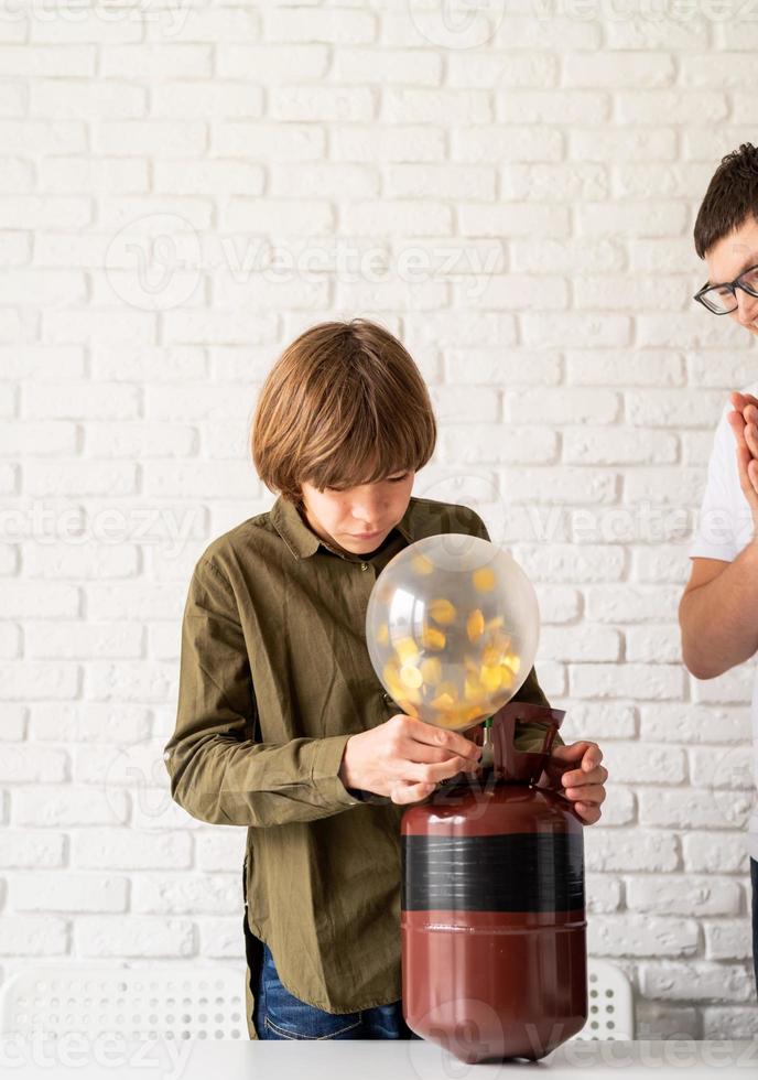 Boy blowing balloon from plastic car bottle at home stock photo