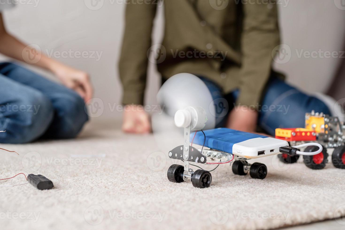 Los muchachos se divierten construyendo coches robot en el taller. foto