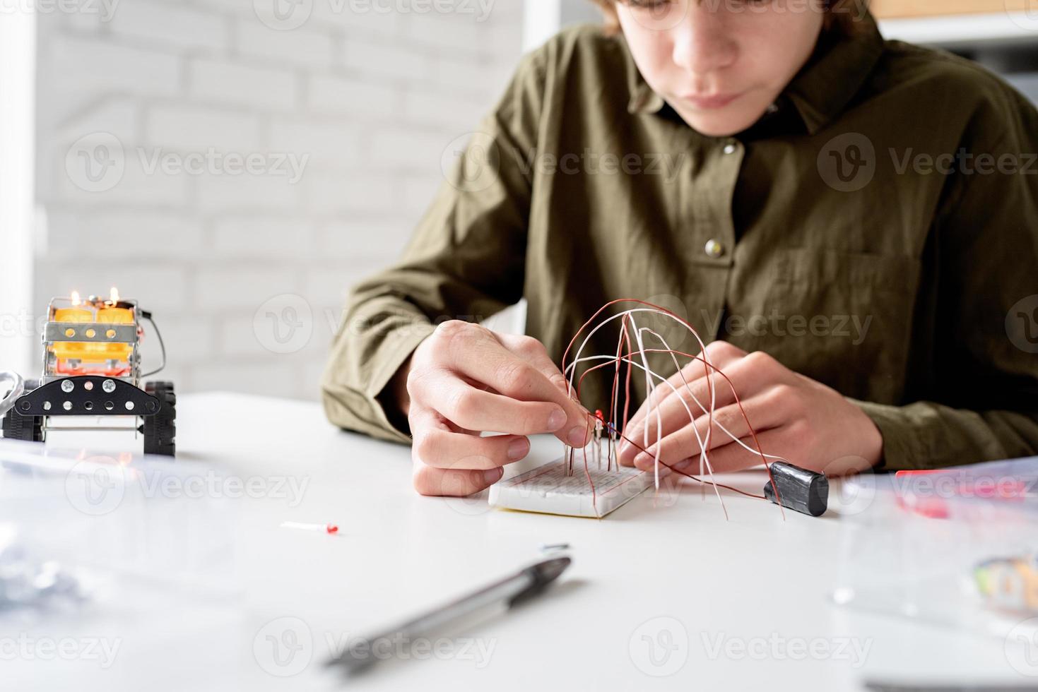 boy working with LED lights on experimental board for science project photo