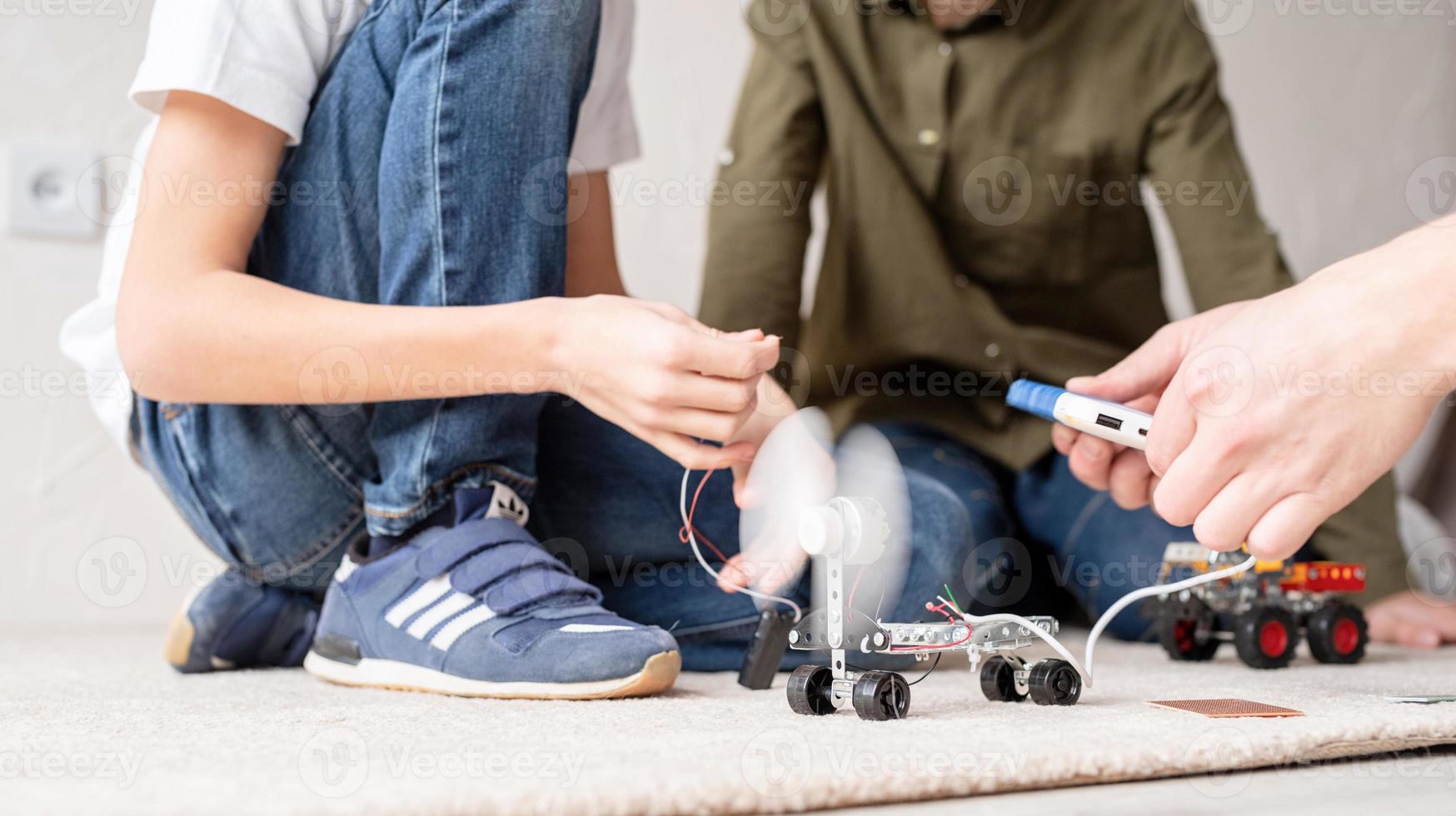 Los muchachos se divierten construyendo coches robot en el taller. foto