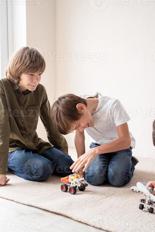 Young boys having fun constructing robot cars sitting on the rug photo