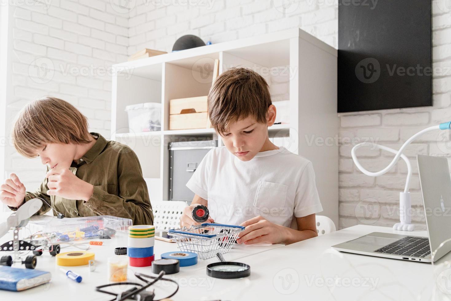 Los muchachos se divierten construyendo coches robot en el taller. foto