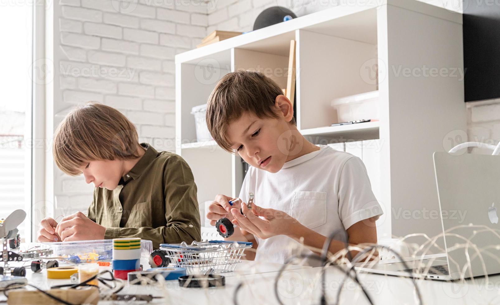 Los muchachos se divierten construyendo coches robot en el taller. foto