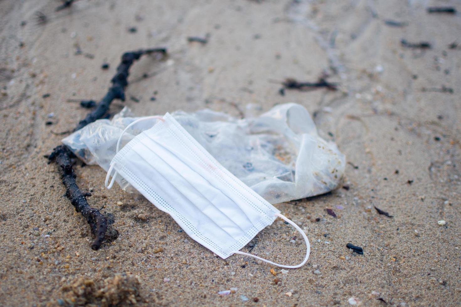 Used mask during Covid 19 was thrown onto the sand beach. subject is burred. photo