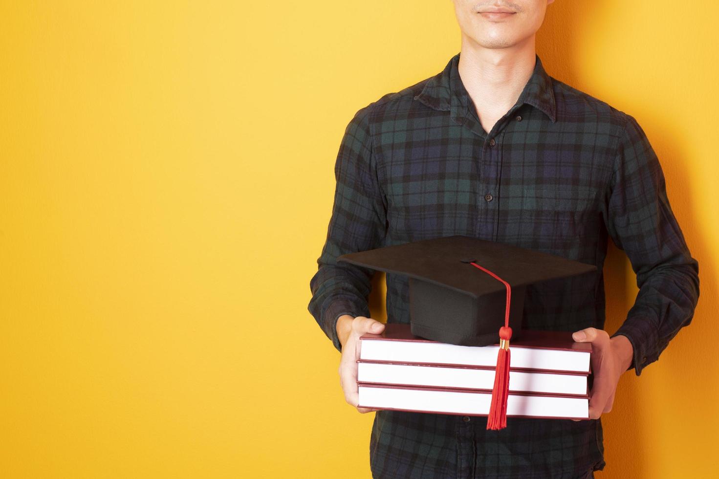 El hombre universitario está contento con la graduación sobre fondo amarillo foto