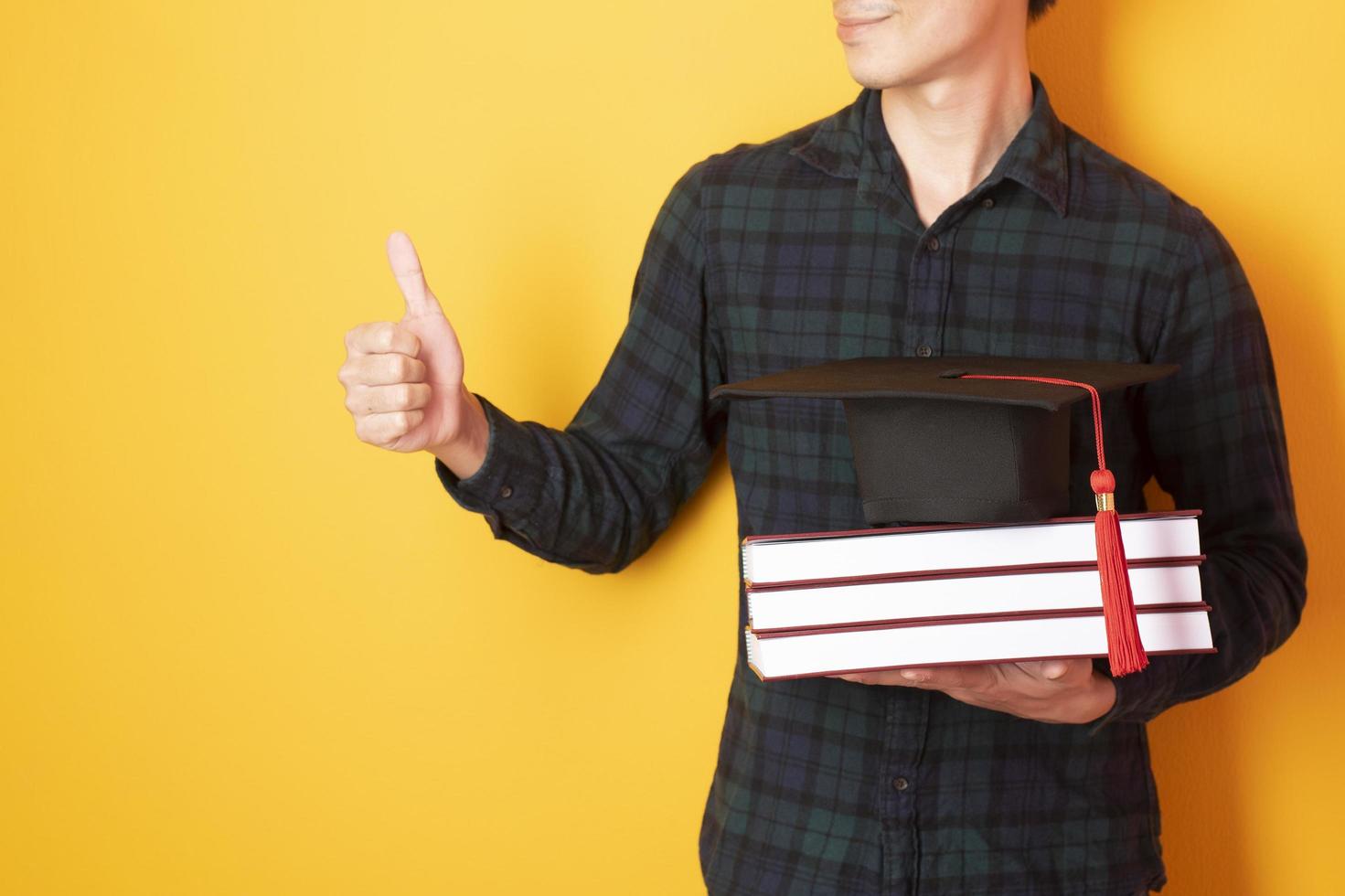 University man is happy with graduation on yellow background photo