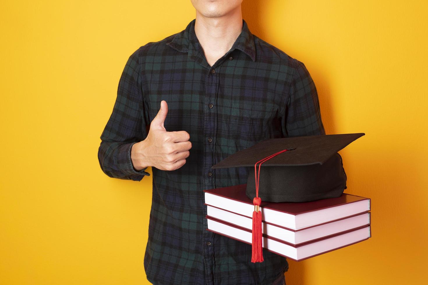 University man is happy with graduation on yellow background photo