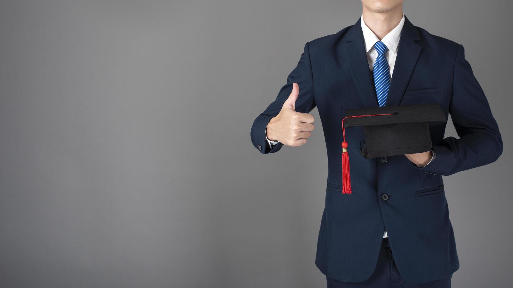 El hombre de negocios está sosteniendo un sombrero de graduación, concepto de educación empresarial foto