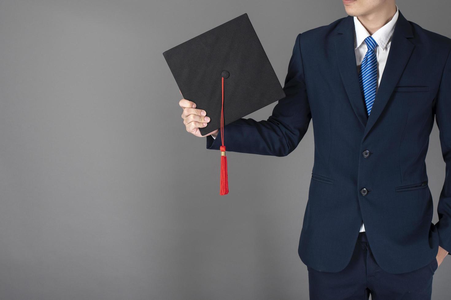 El hombre de negocios está sosteniendo un sombrero de graduación, concepto de educación empresarial foto