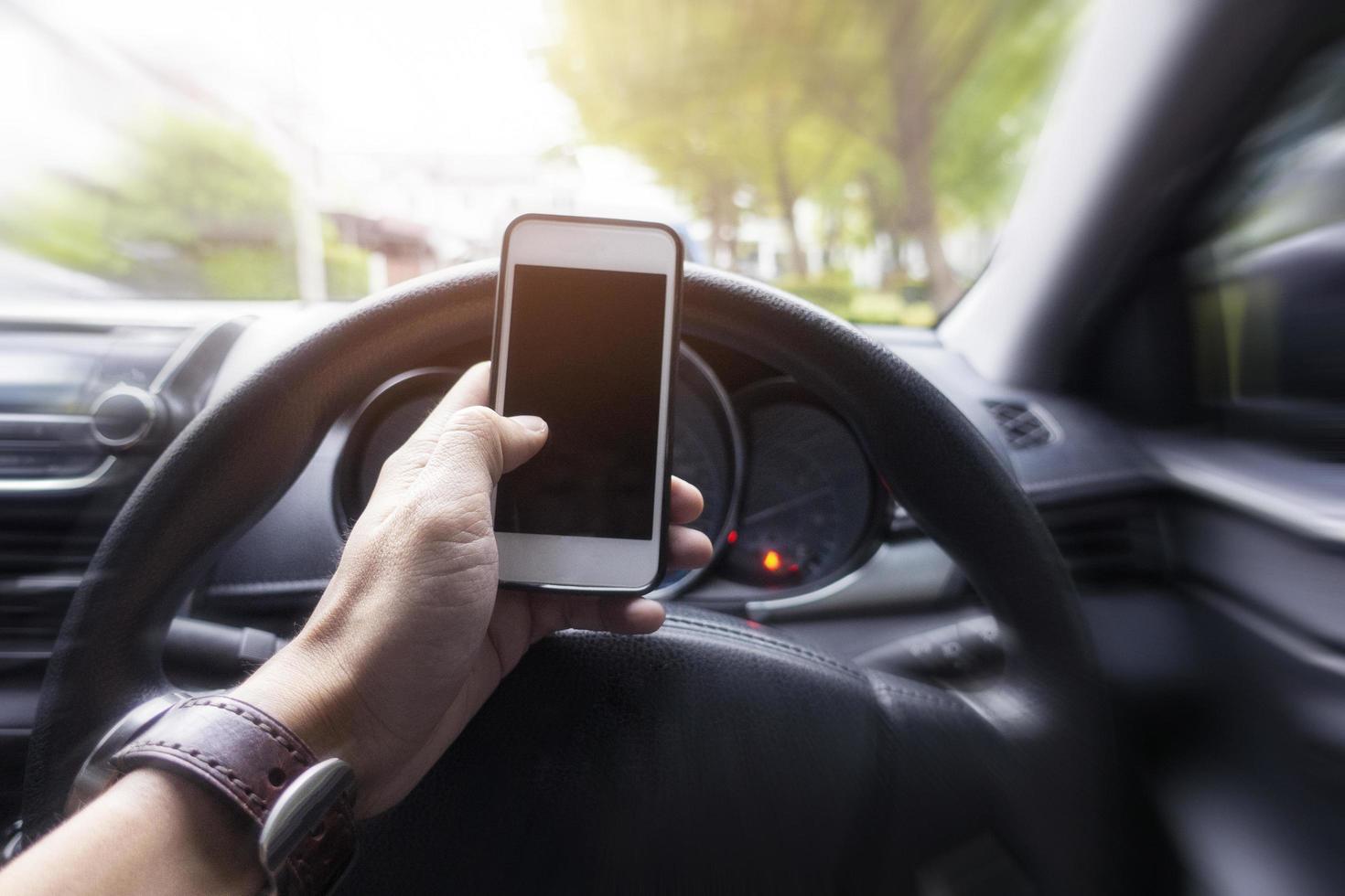 Close up man hand using smart phone while  he is driving the car photo