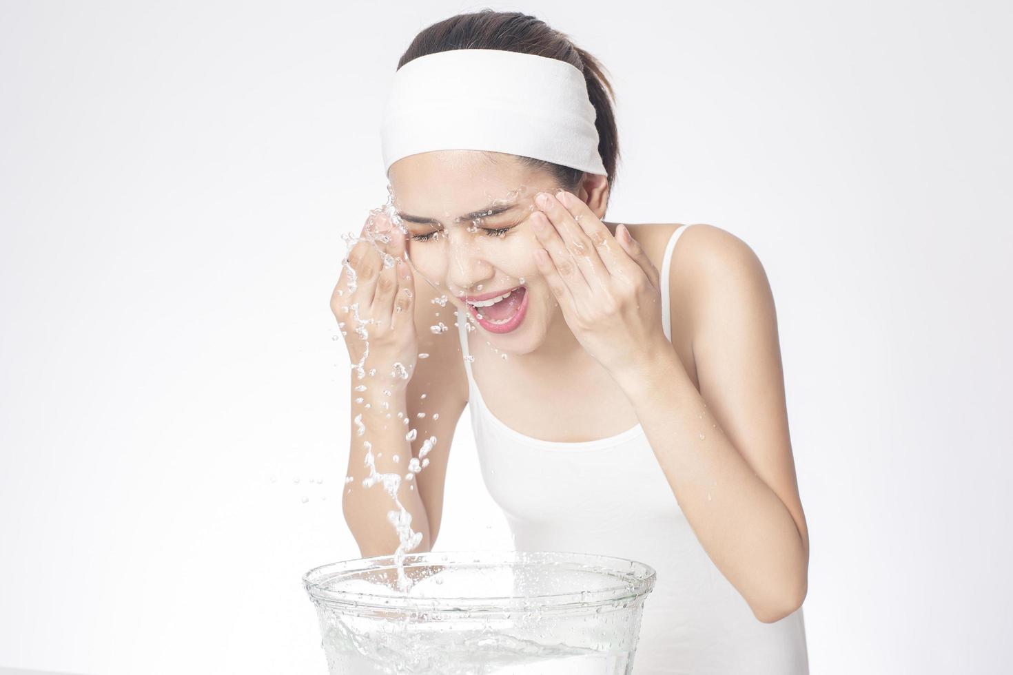 Beautiful woman is washing her face on white background photo