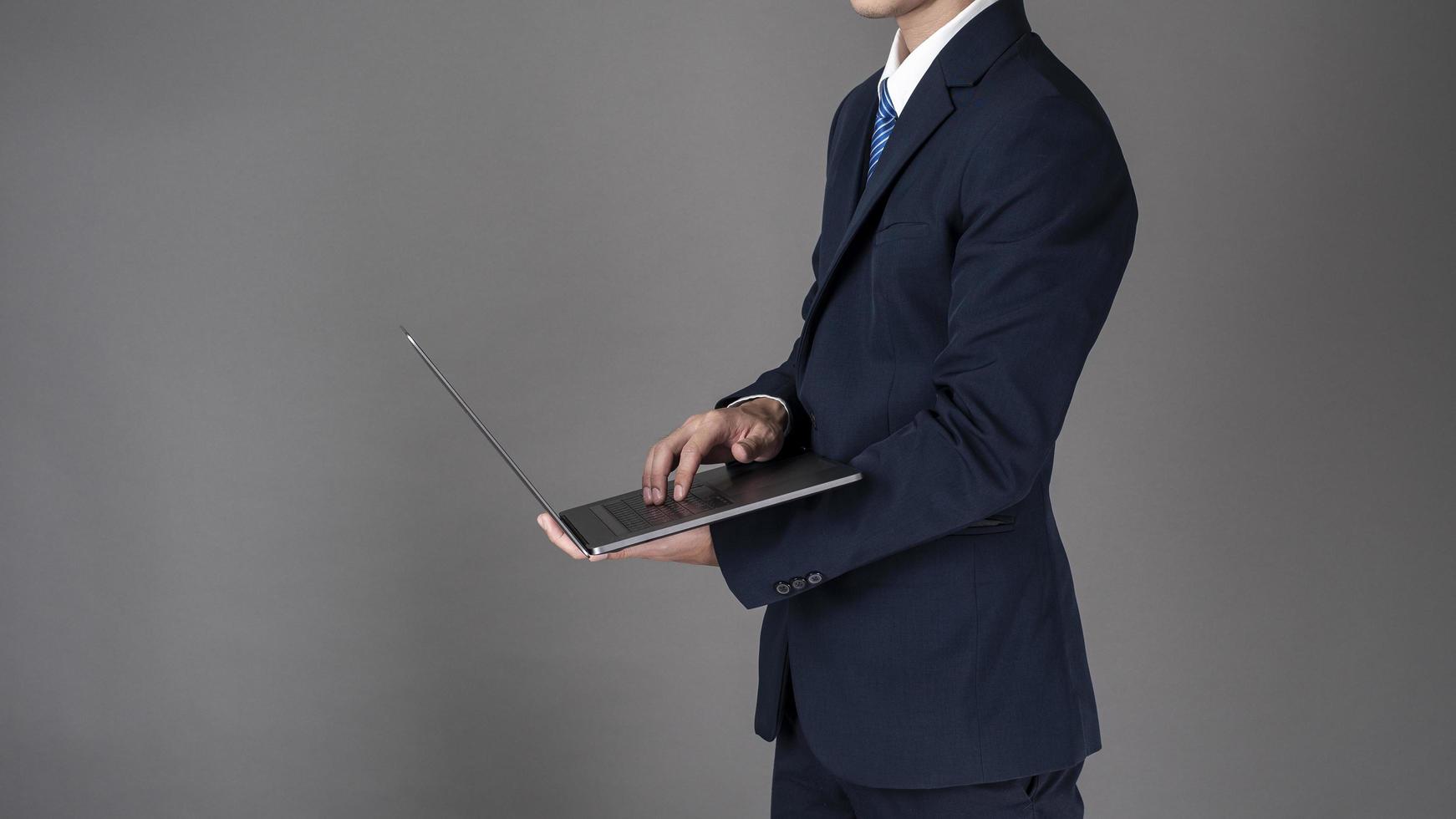 Business man is using laptop ,grey background in studio photo