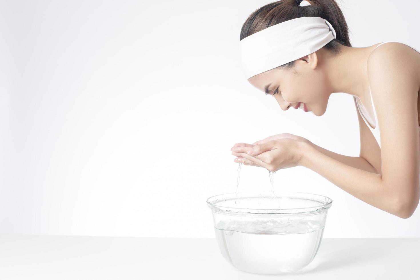 Beautiful woman is washing her face on white background photo