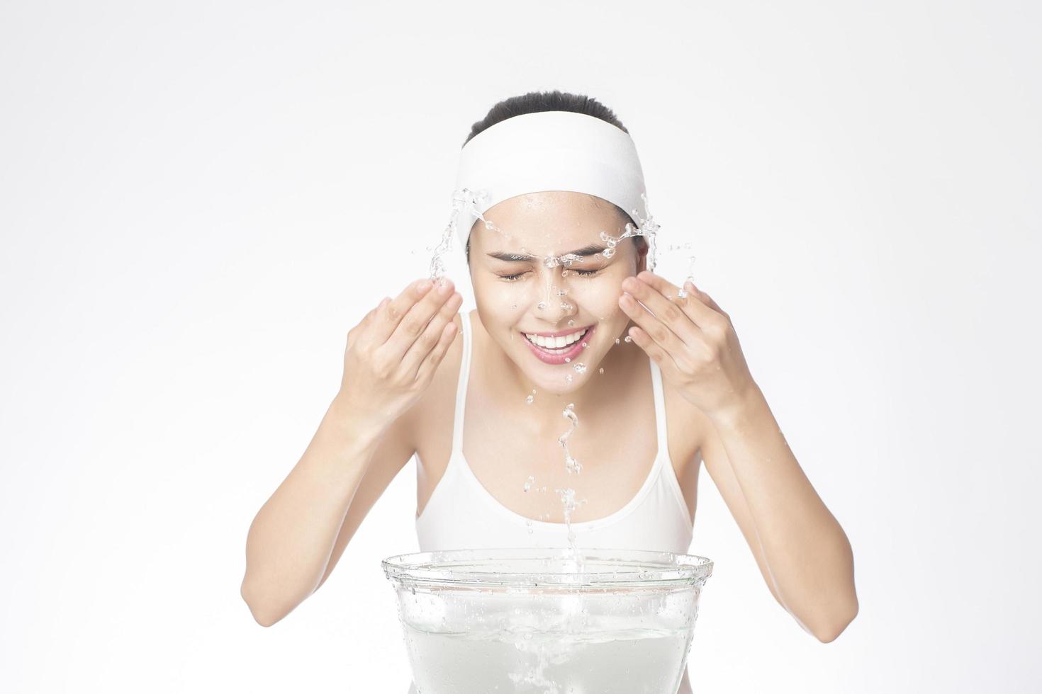 Beautiful woman is washing her face on white background photo