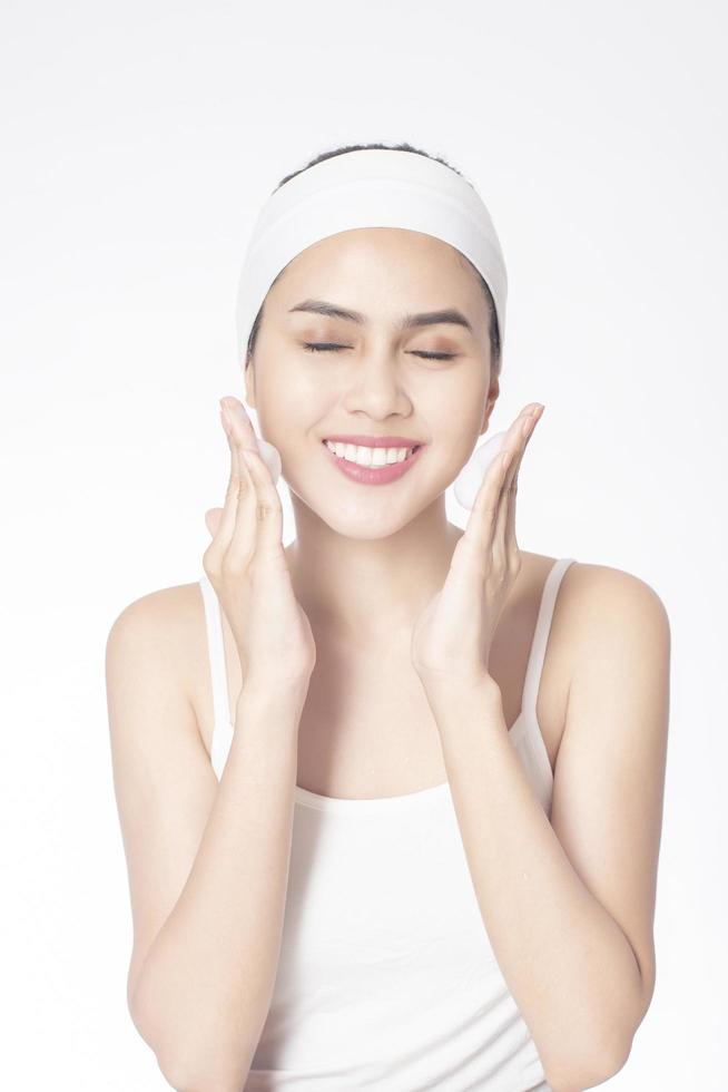 Beautiful woman is washing her face on white background photo