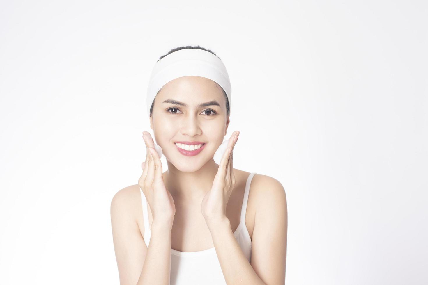 Beautiful woman is washing her face on white background photo