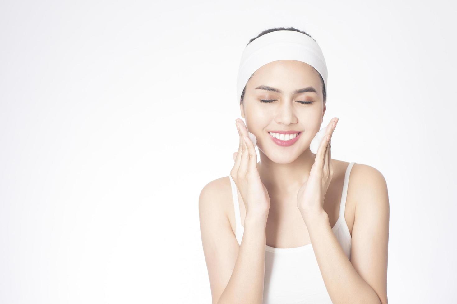 Beautiful woman is washing her face on white background photo