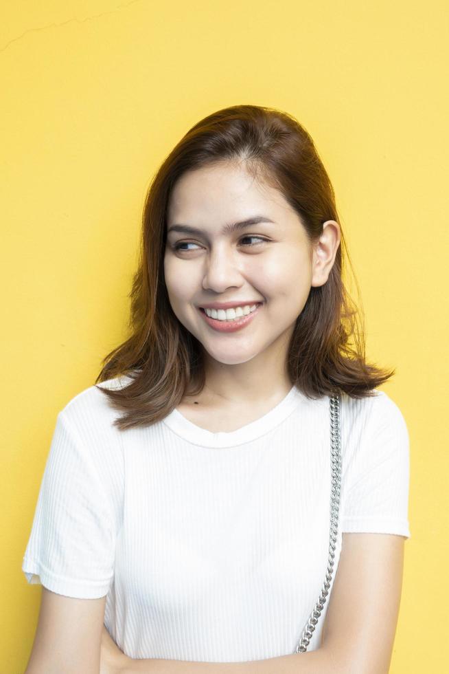 Retrato de hermosa estudiante universitaria está sonriendo sobre fondo de pared amarilla foto