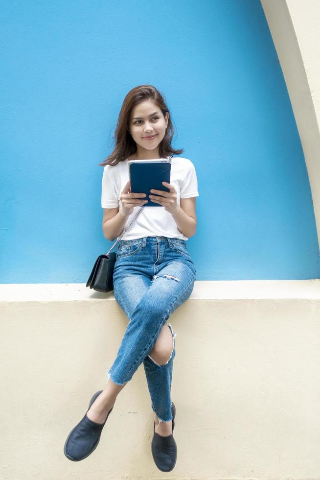Portrait of beautiful university student is smiling on blue wall background photo