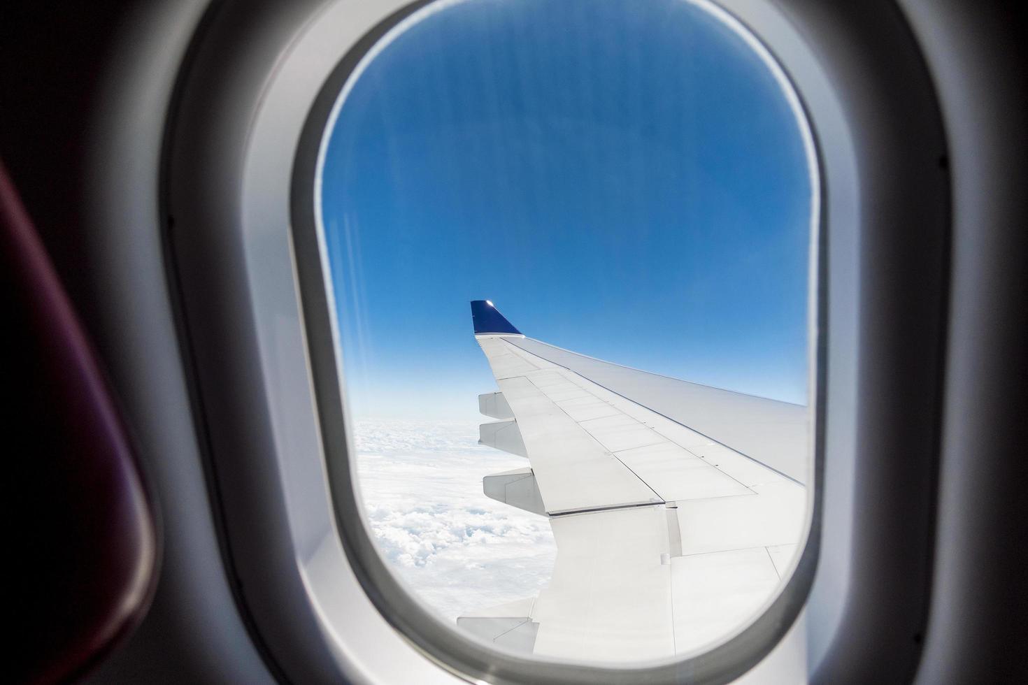 Beautiful view of cloudscape and airplane wing seen through window of an airplane photo