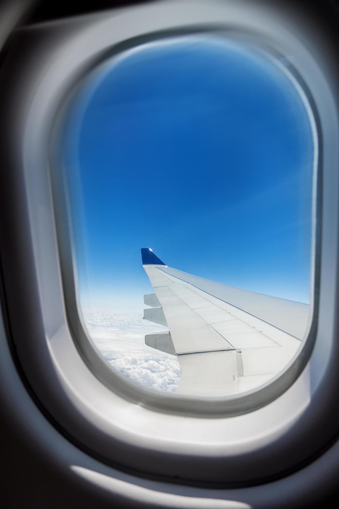 Beautiful view of cloudscape and airplane wing seen through window of ...