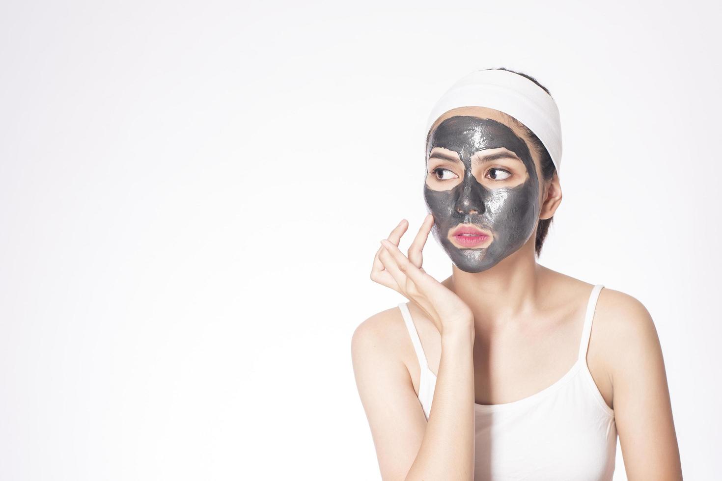 Bella mujer enmascarando su rostro sobre fondo blanco. foto