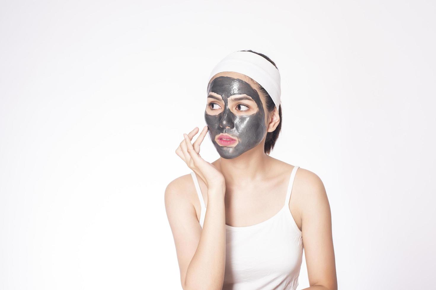 Bella mujer enmascarando su rostro sobre fondo blanco. foto