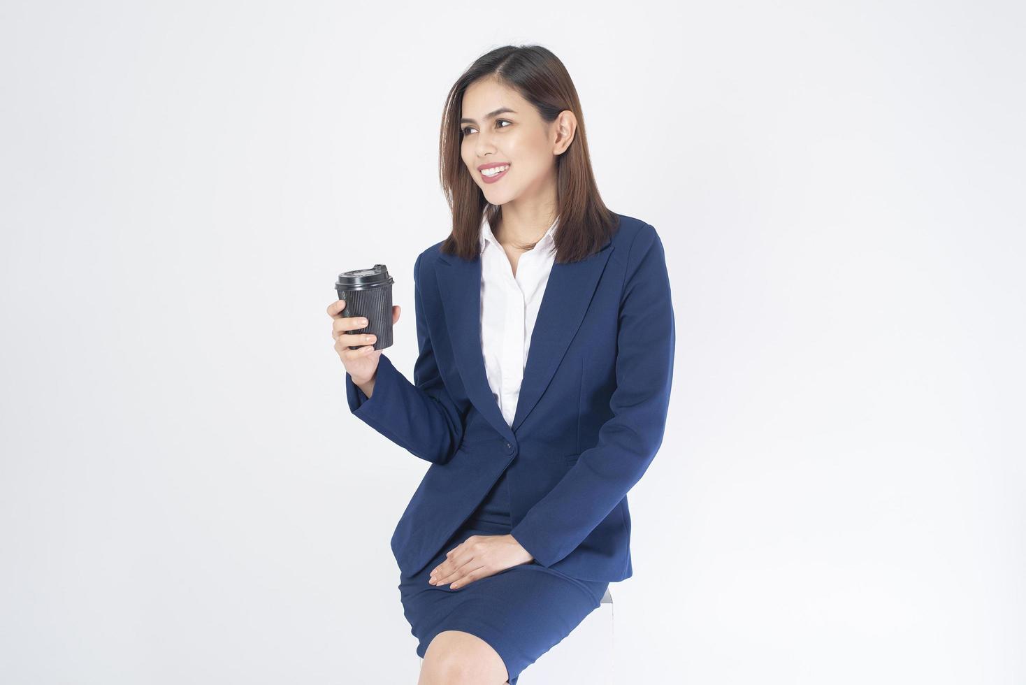 Mujer en traje azul está bebiendo café sobre fondo blanco. foto