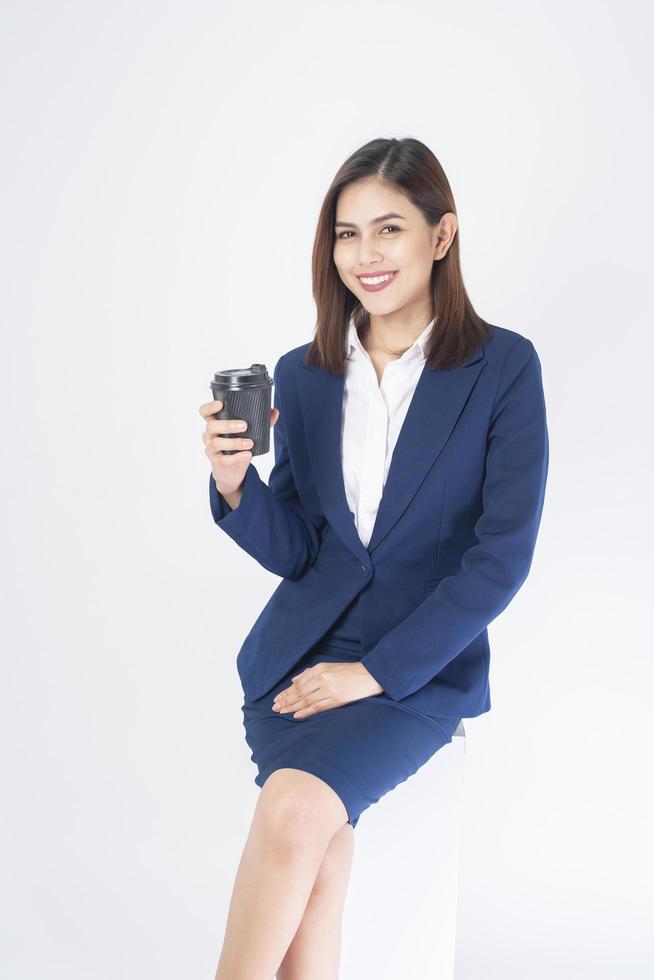 Mujer en traje azul está bebiendo café sobre fondo blanco. foto