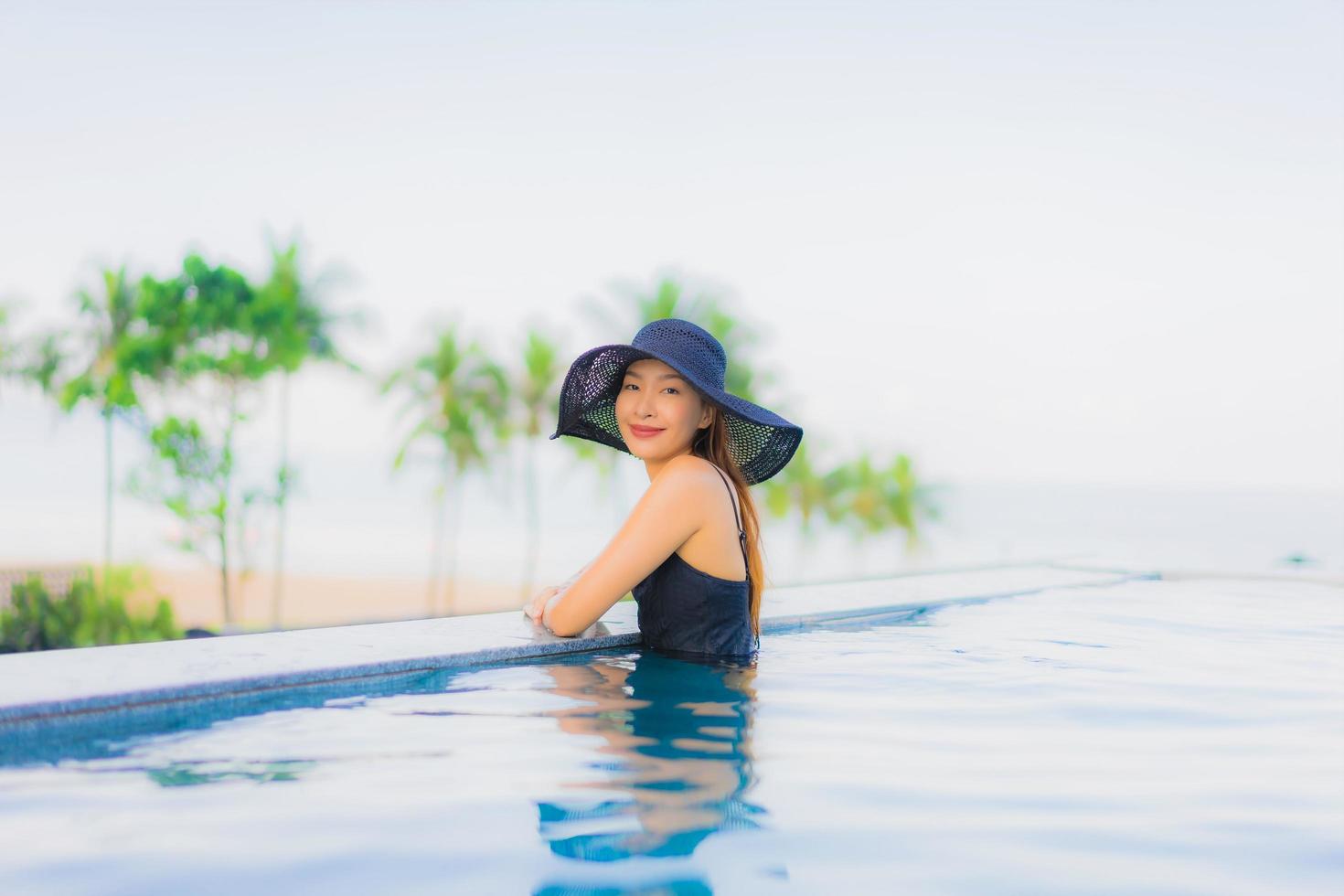 retrato, hermoso, joven, mujeres asiáticas, feliz, sonrisa, relajarse, piscina al aire libre, en, hotel foto