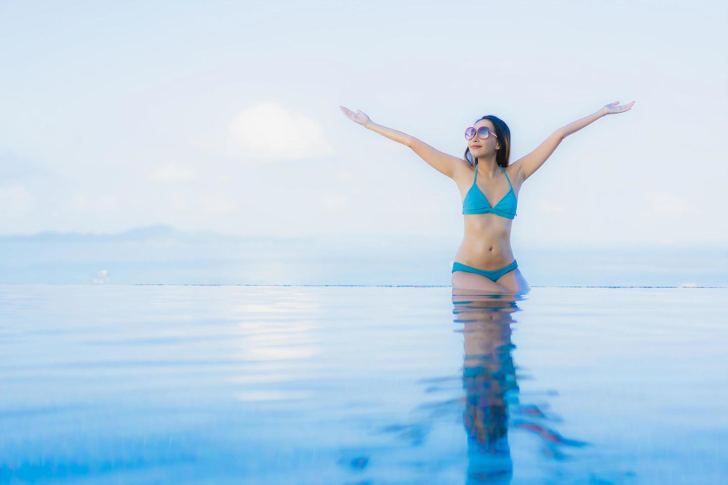 Retrato hermosas mujeres asiáticas jóvenes sonrisa feliz relajarse piscina al aire libre en el resort foto