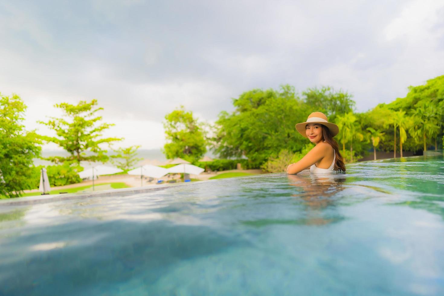 retrato, hermoso, joven, mujeres asiáticas, feliz, sonrisa, relajarse, alrededor, piscina al aire libre, en, hotel foto