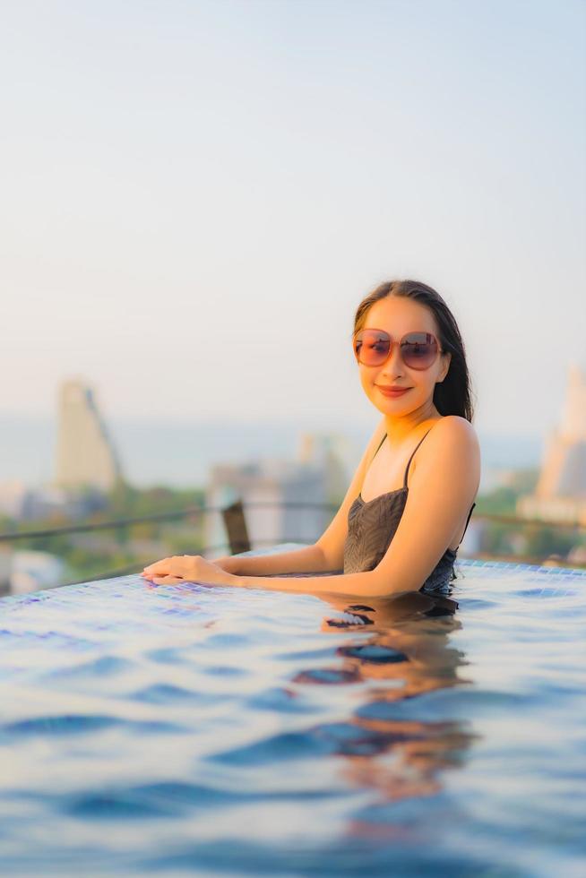 retrato, hermoso, joven, mujeres asiáticas, feliz, sonrisa, relajarse, piscina al aire libre, en, hotel foto