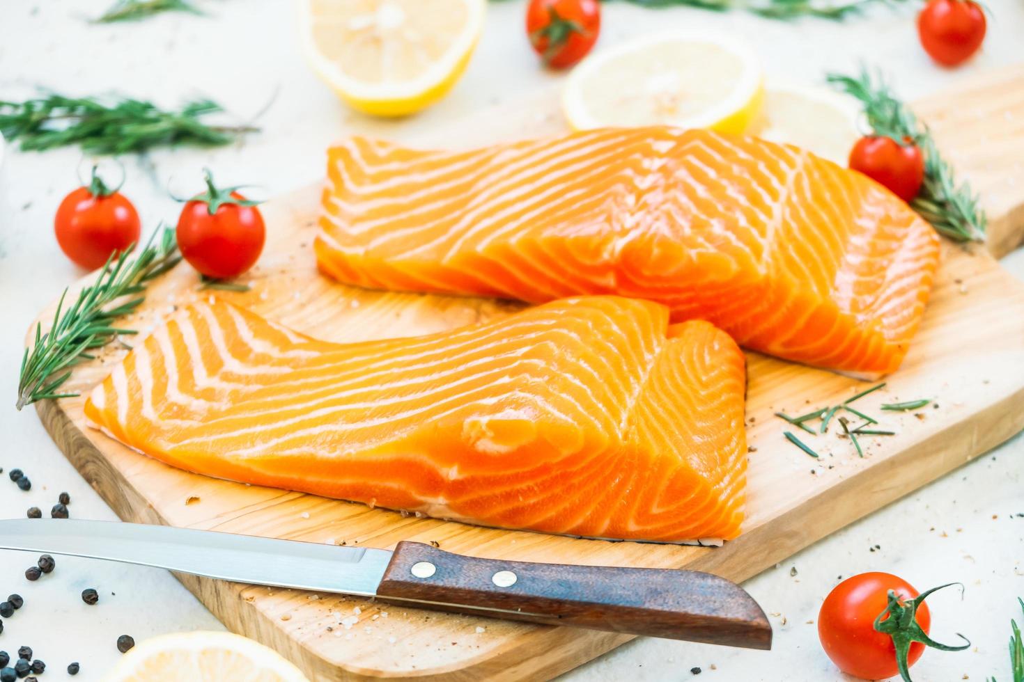 Filete de carne de salmón crudo y fresco sobre tabla de cortar de madera foto