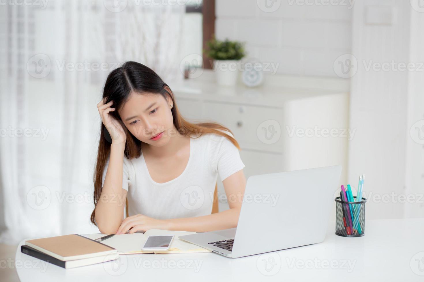 Dolor de cabeza de joven mujer asiática durante el trabajo en la computadora portátil con fecha límite en el escritorio en casa, mujer de negocios con fracaso agotada y cansada, estresada y preocupada, frustrada y sin éxito. foto