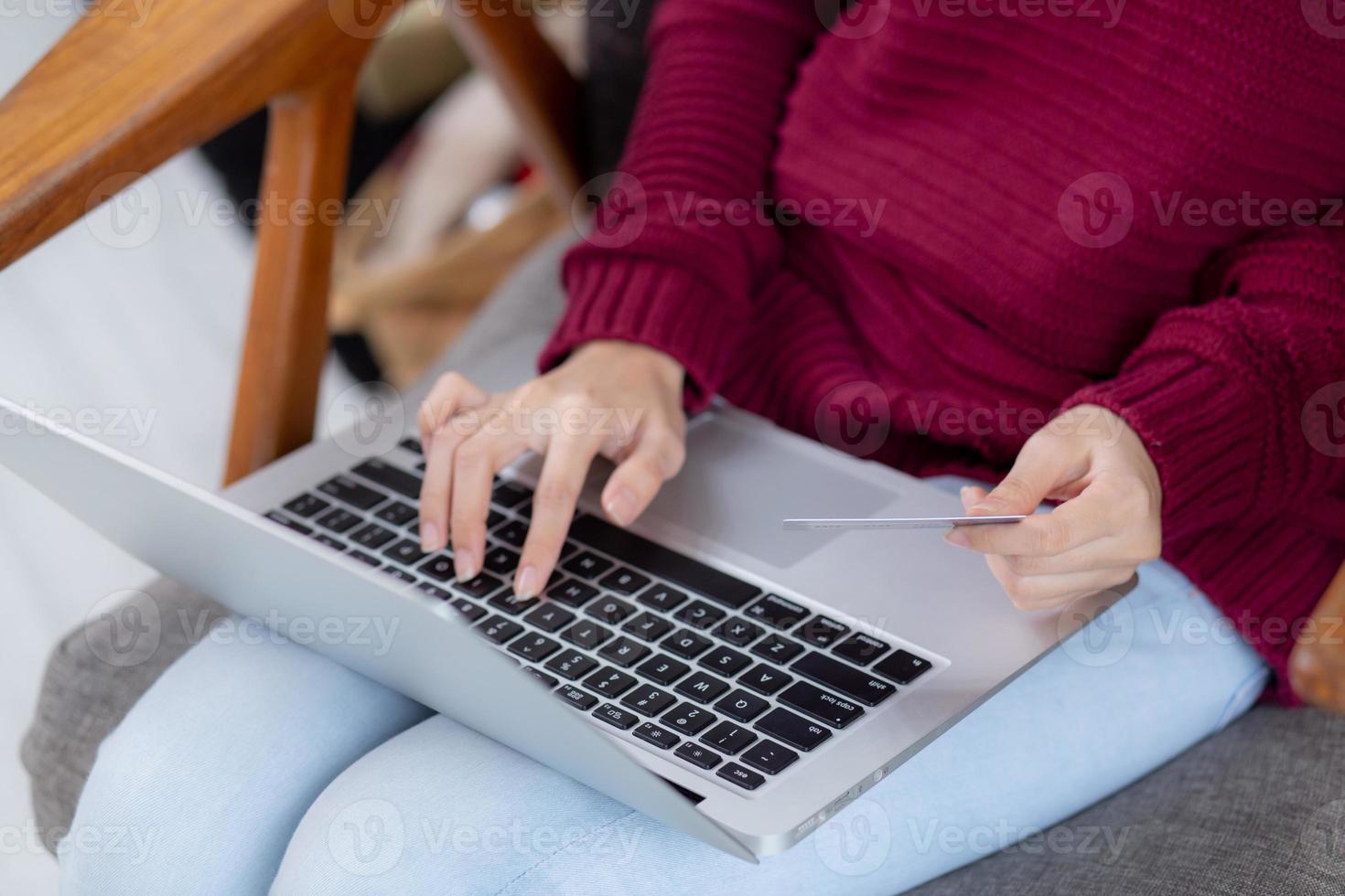 Closeup hand of young asian woman online shopping in Christmas with credit card on laptop computer, female buying and payment with debit card, xmas in holiday, happy new year, customer with purchase. photo