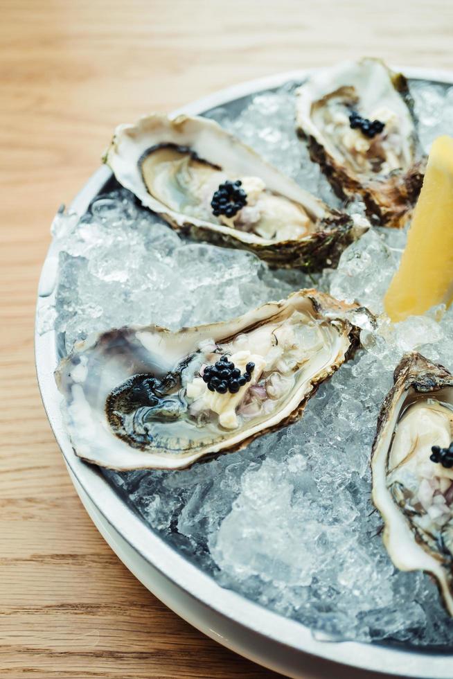 Ostra cruda y fresca con caviar encima y limón. foto