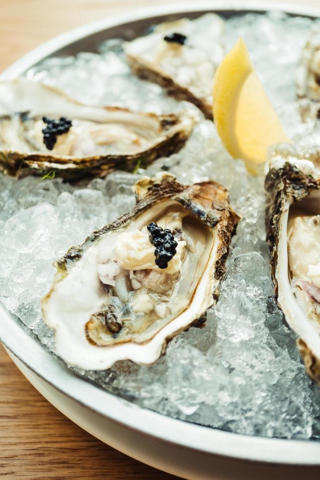 Ostra cruda y fresca con caviar encima y limón. foto