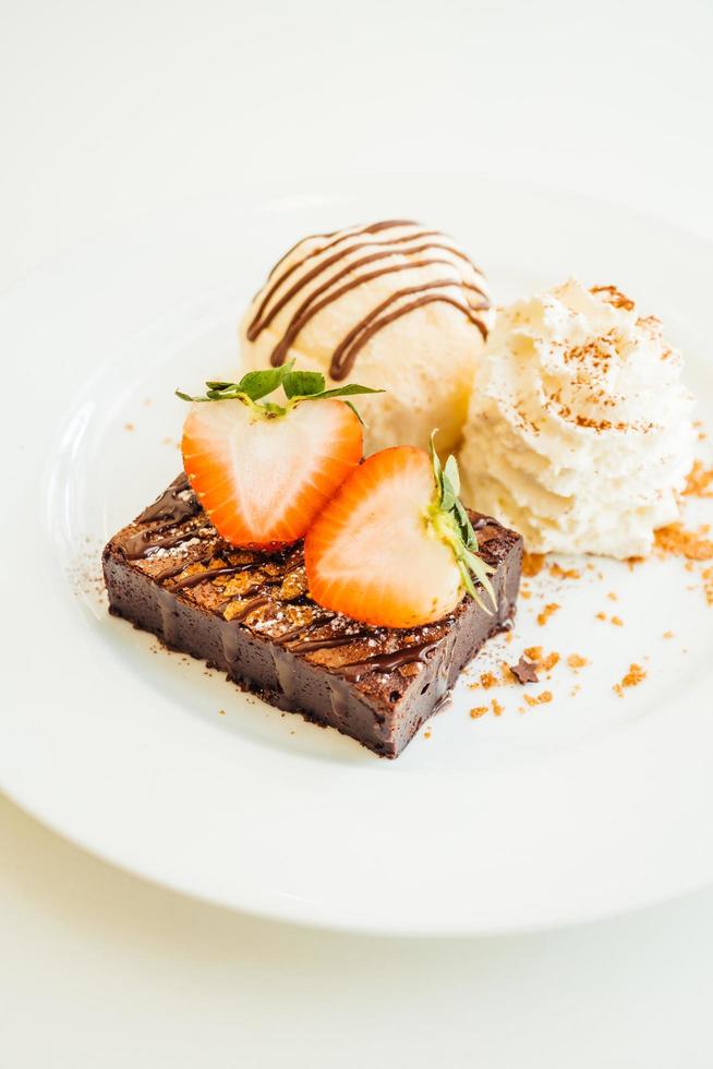 Vanilla ice cream with chocolate brownie cake with strawberry on top photo