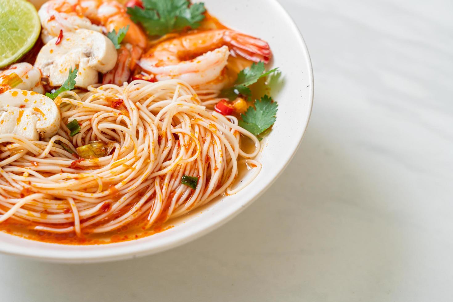 fideos con sopa picante y camarones en un tazón blanco, o tom yum kung - estilo de comida asiática foto