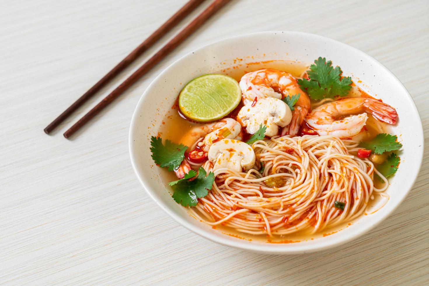 Noodles with spicy soup and shrimps in white bowl, or Tom Yum Kung - Asian food style photo