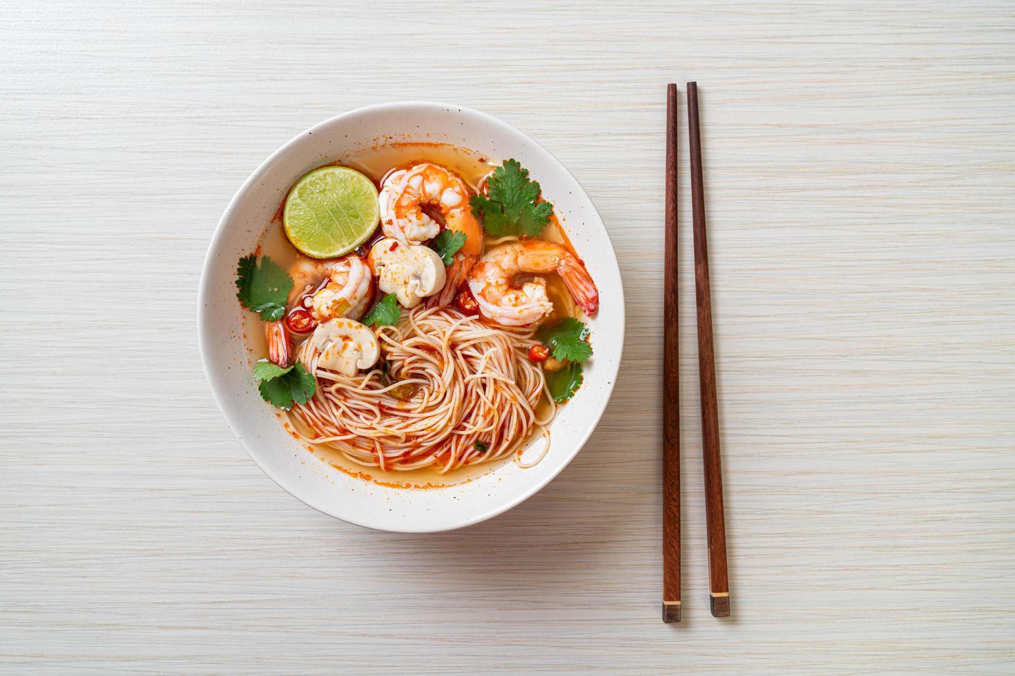 Noodles with spicy soup and shrimps in white bowl, or Tom Yum Kung - Asian food style photo