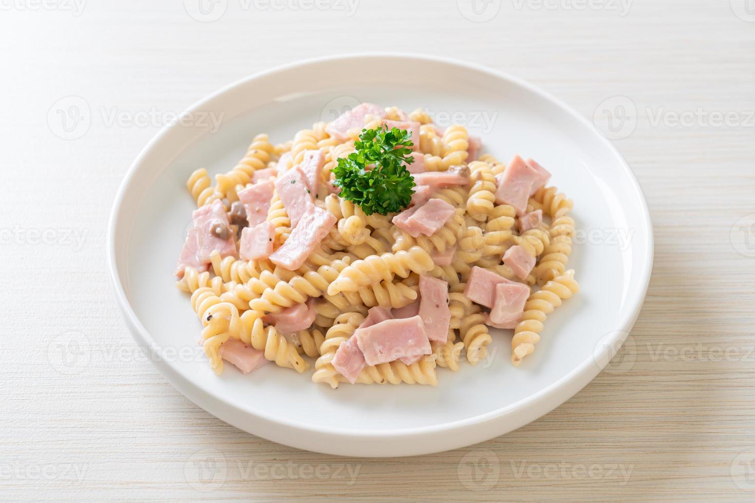 Spirali o salsa de crema de champiñones de pasta con jamón - estilo de comida italiana foto