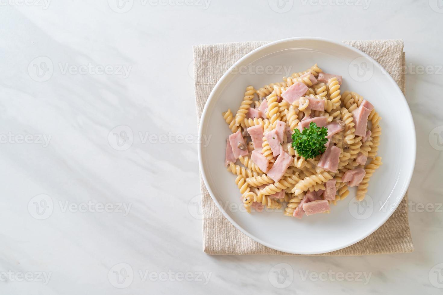 Spirali o salsa de crema de champiñones de pasta con jamón - estilo de comida italiana foto