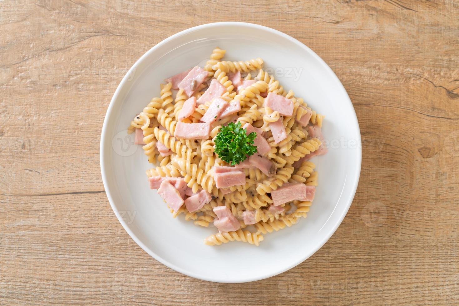 Spirali o salsa de crema de champiñones de pasta con jamón - estilo de comida italiana foto