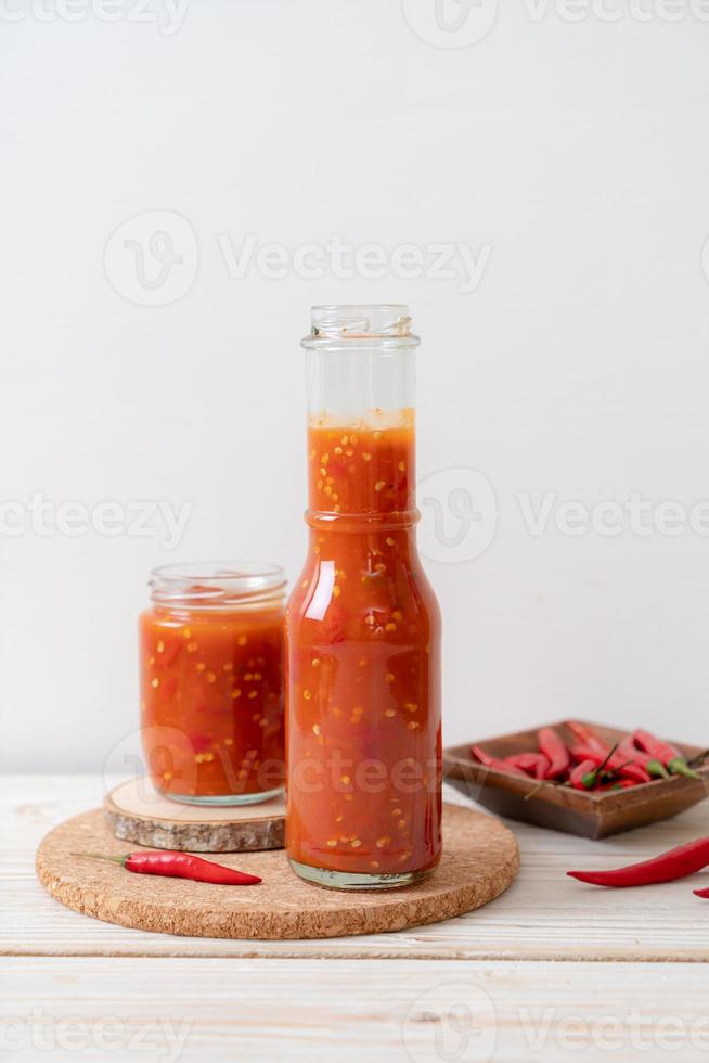 Chile o salsa de chile en botella y tarro sobre fondo de madera foto