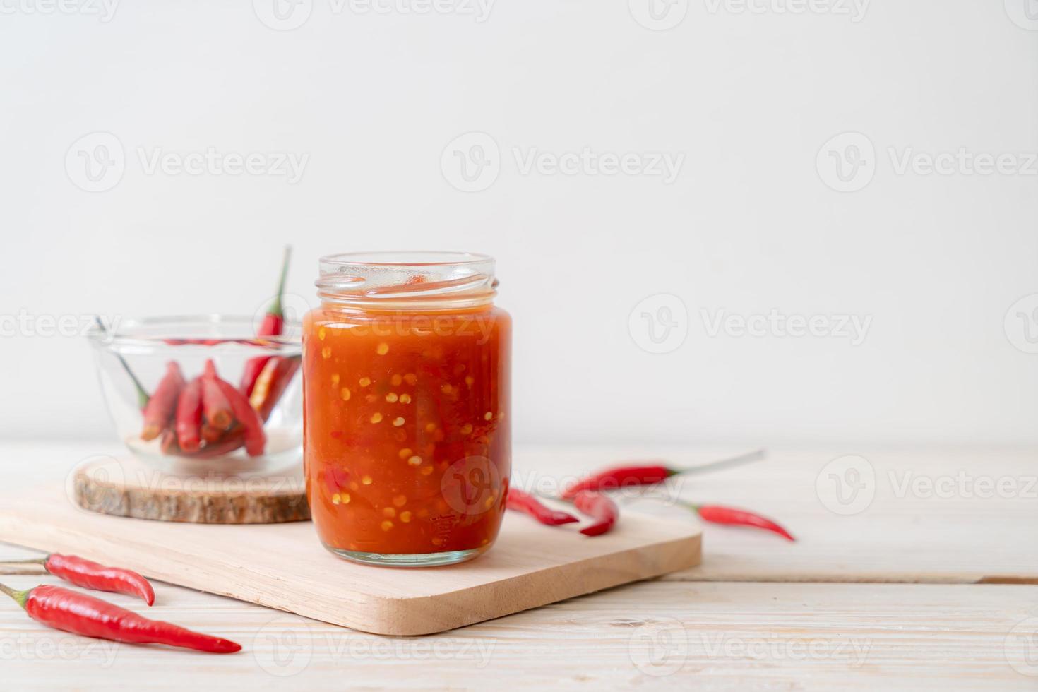 Chili or chili sauce in bottle and jar on wood background photo